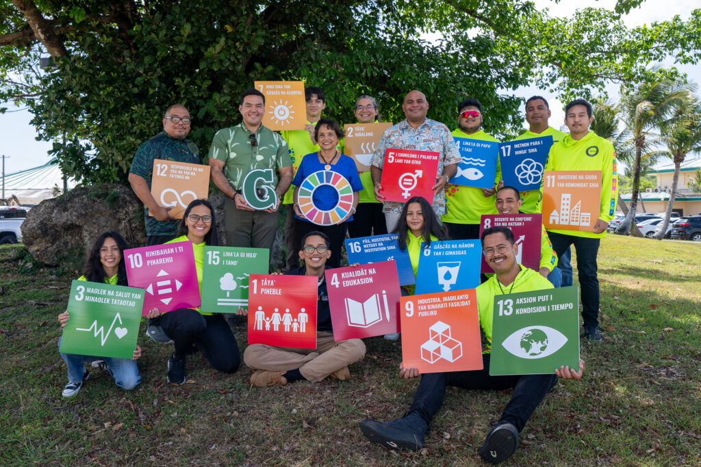 The 5th cohort of the Guam Green Growth Kupu Conservation Corps, along with Governor Lou Leon Guerrero, Lieutenant Governor Josh Tenorio, UOG Center for Island Sustainability and Sea Grant Director Austin Shelton, PhD, and UOG Center for Island Sustainability and Sea Grant Associate Director for Communications and Engagement Kyle Mandapat, hold signs displaying the 17 UN Sustainable Development Goals in CHamoru.