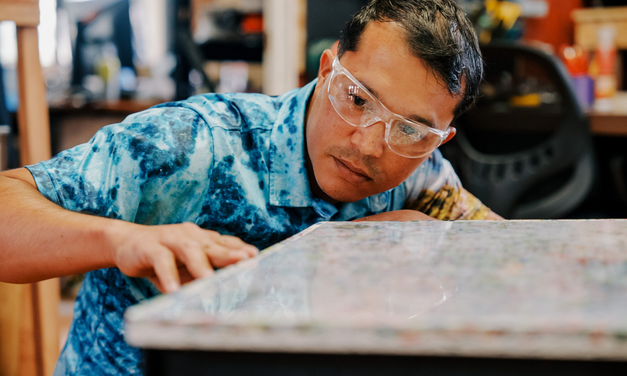 Navigating Home fellow Justin Cruz, who is assigned to the G3 Makerspace & Innovation Hub, checks the surface of the desk prototype that he created. The G3 Makerspace is collecting recyclable plastics to support a new project aimed at refurbishing school desks.