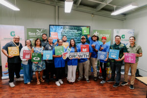The second G3 GROW Corps cohort and UOG CIS & Sea Grant leadership pose holding colourful Sustainable Development Goal signs and a Guam Green Growth plaque.